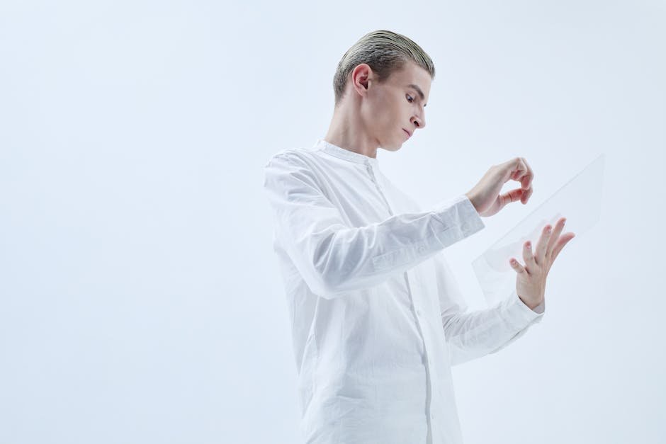 Young man interacting with a transparent digital tablet in a minimalist studio setting.